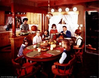 A group of people sitting around a table in a kitchen.