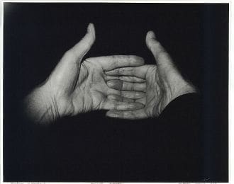 A black and white photograph of two hands reaching out.