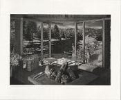 A black and white photo of a living room with a fireplace.