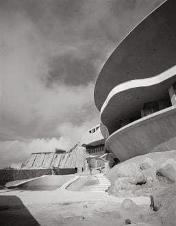 A black and white photo of a building on a hill.