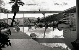 A black and white photo of a pool and palm trees.