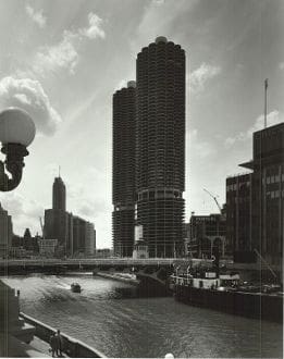 A black and white photo of a river and tall buildings.