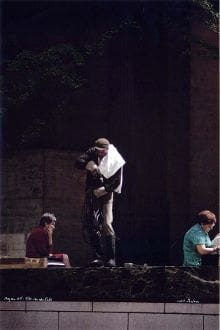 A man holding onto a statue while standing on the ground.