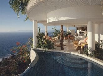 A pool with a view of the ocean and a deck.