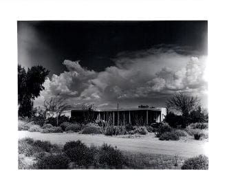 A black and white photo of a building with clouds in the background.