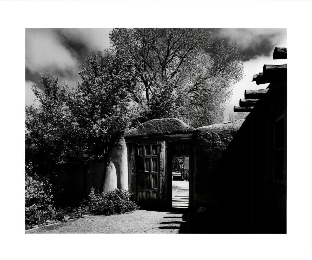 A black and white photo of a building with trees in the background.