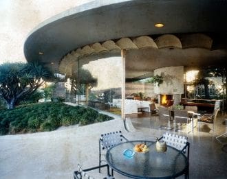 A table and chairs in front of an outdoor fireplace.