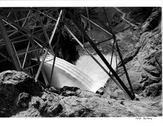 A black and white photo of a waterfall in the middle of a cave.