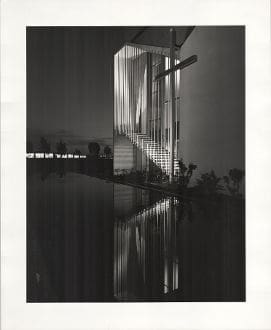 A black and white photo of a building with water