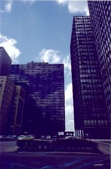 A view of some buildings and cars driving down the street.