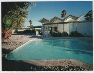 A pool with a large house in the background.