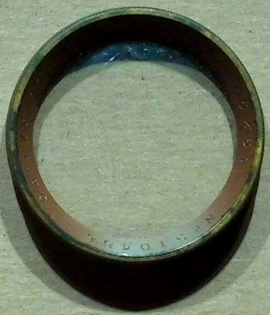 Close-up of a circular metal ring with a worn surface on a gray background.