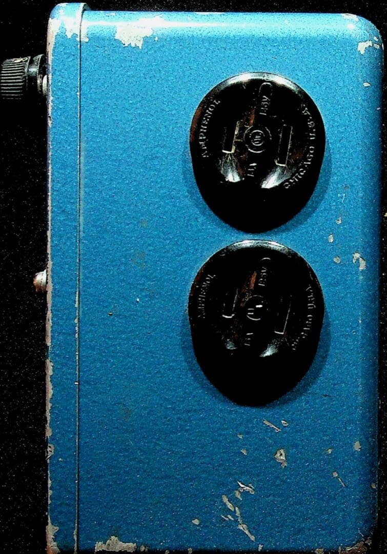 Close-up of two black rotary dials on a blue panel.