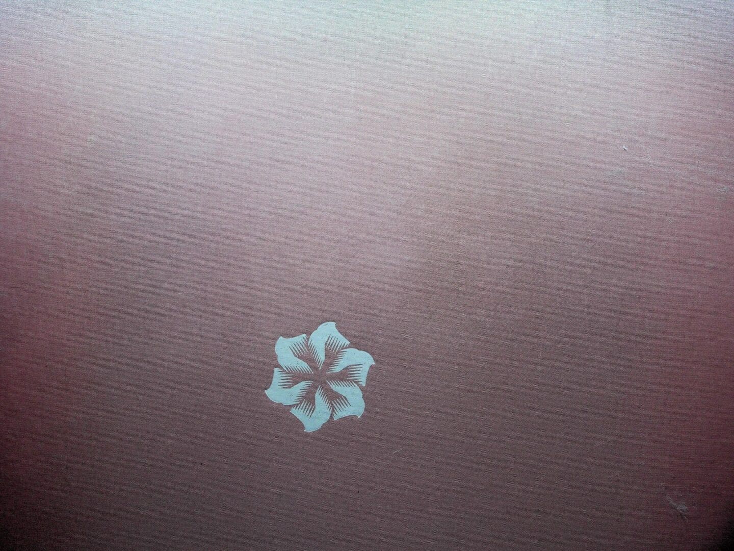 Single small white floral emblem on mauve fabric