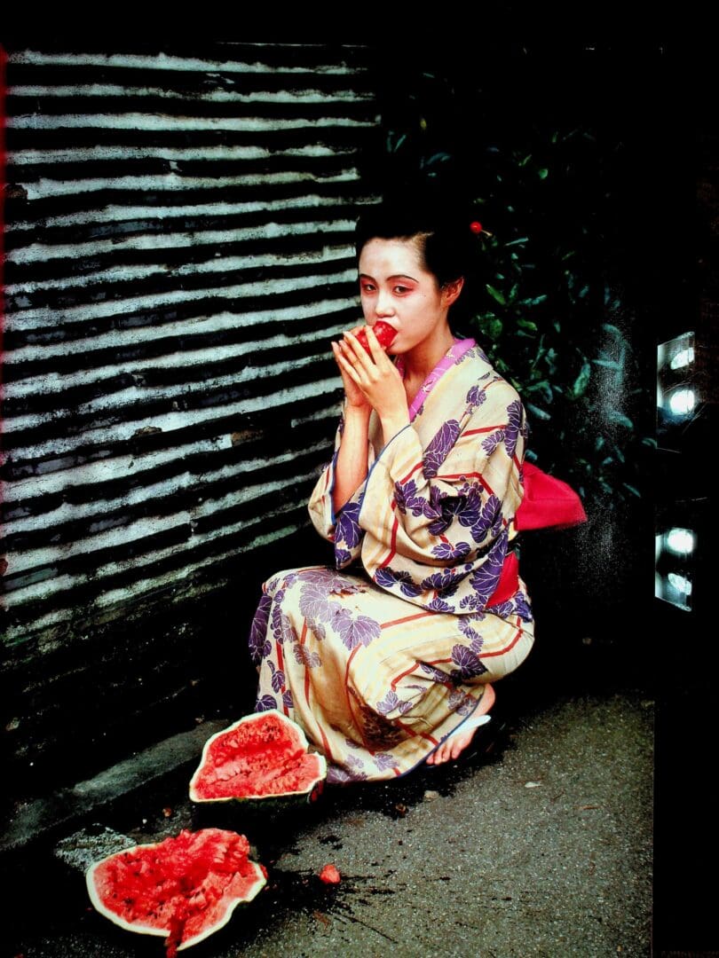 Woman in kimono eating watermelon on street